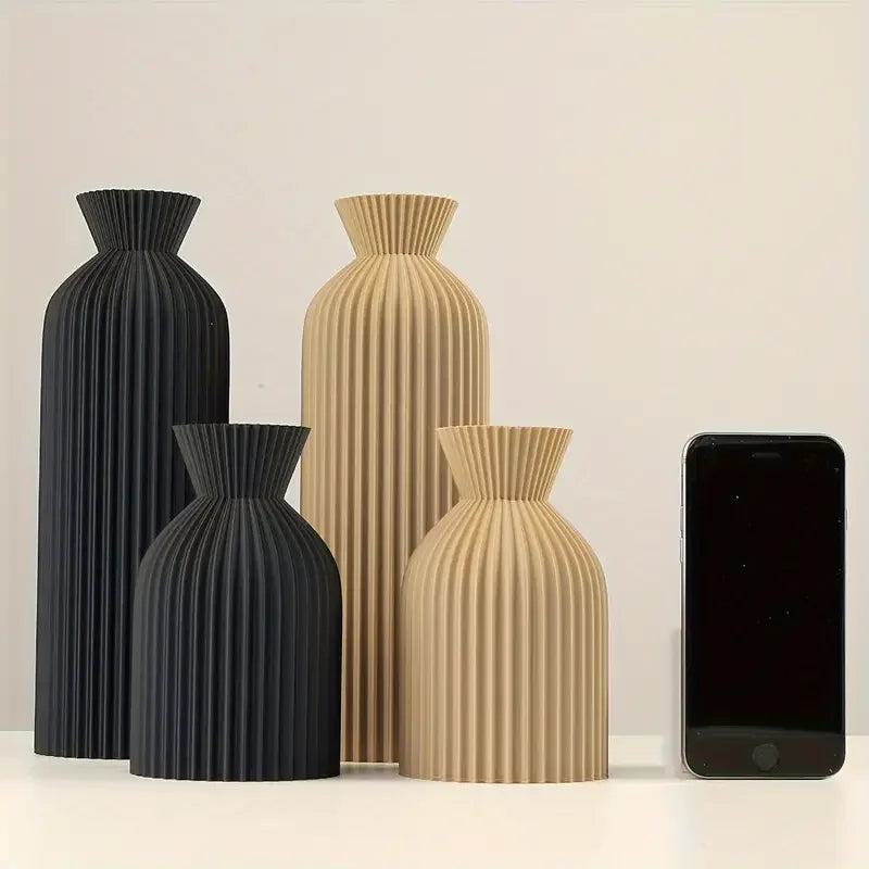 Jarrones decorativos modernos de color negro y beige con diseño acanalado junto a un móvil
