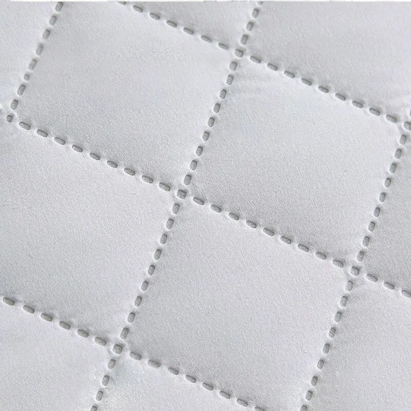 Acercamiento de funda acolchada blanca para colchón, costura en patrón de cuadros, accesorios para el hogar.