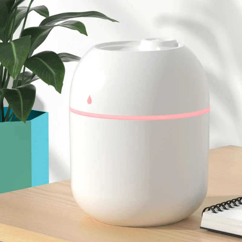 Humidificador LED blanco para hogar moderno sobre mesa de madera, junto a planta y libreta