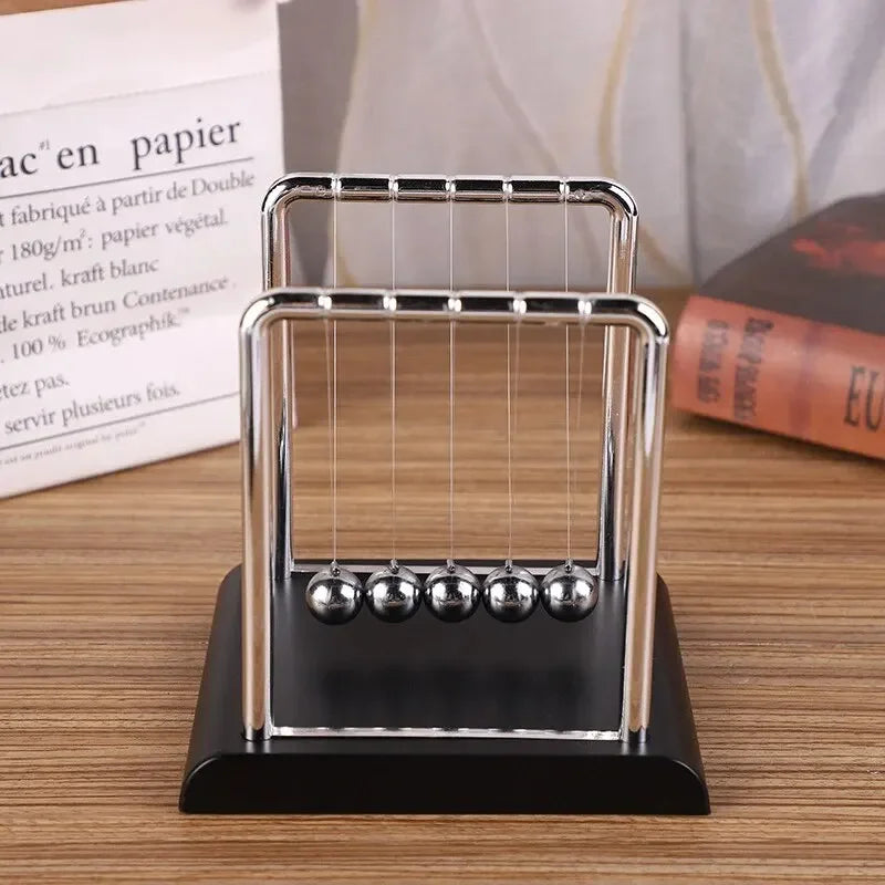 Péndulo de Newton metálico sobre mesa de madera, accesorio decorativo para hogar moderno