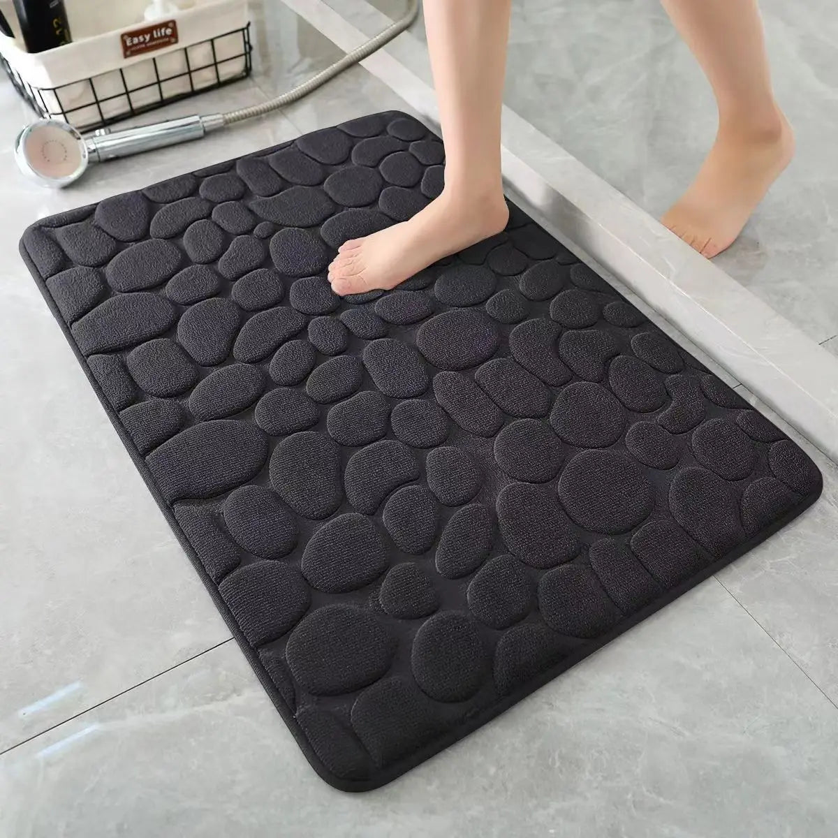 Alfombra antideslizante negra textura piedras para baño moderno en piso de mármol