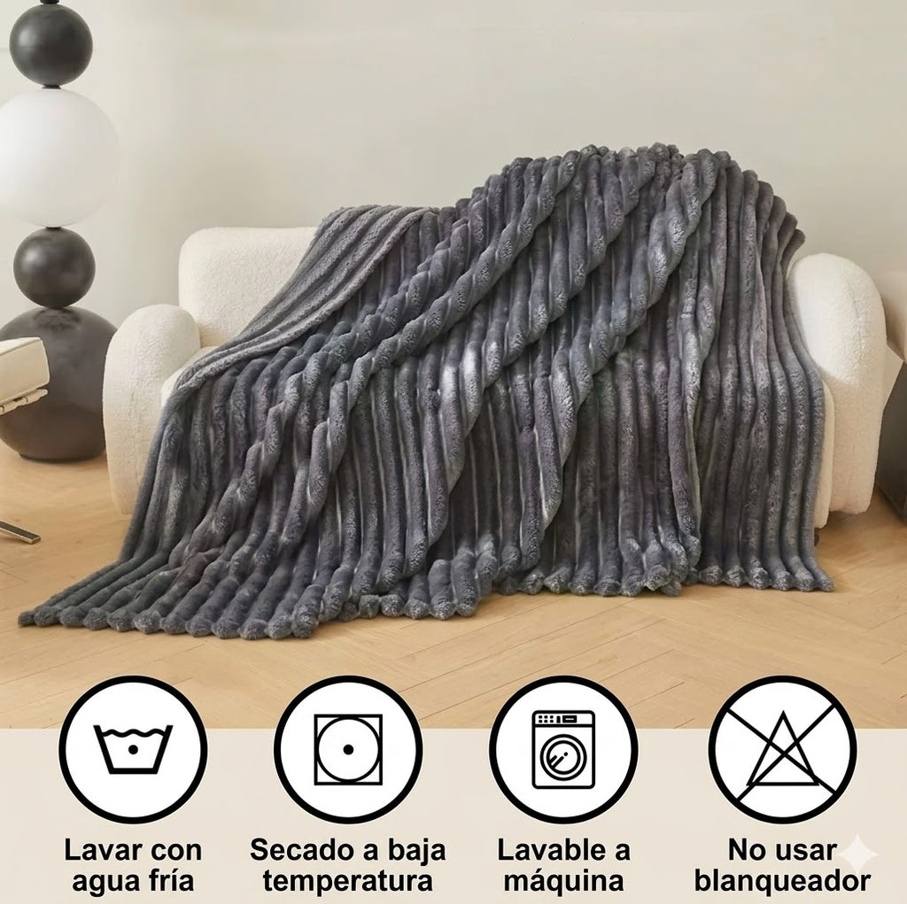 Manta gris de felpa sobre sofá moderno, con instrucciones de cuidado visibles, decoración hogar.