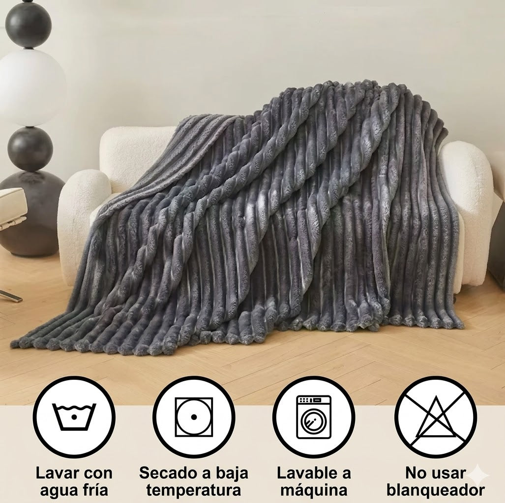Manta gris de felpa sobre sofá moderno, con instrucciones de cuidado visibles, decoración hogar.
